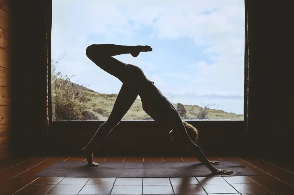 Person practising yoga indoors near large window.
