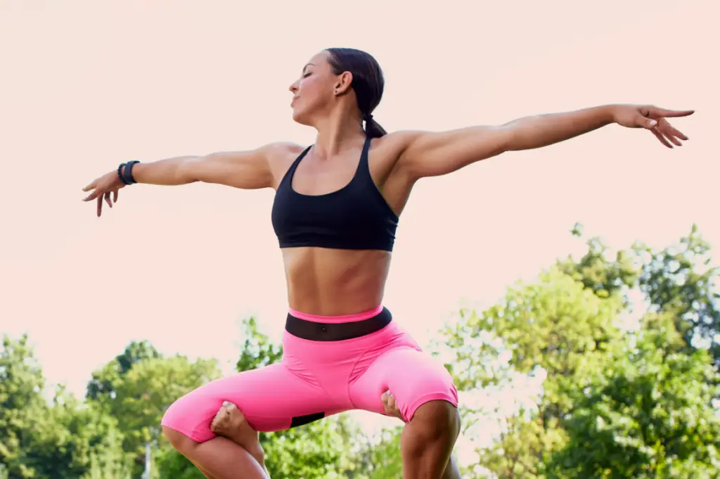 Woman doing yoga outdoors in pink leggings